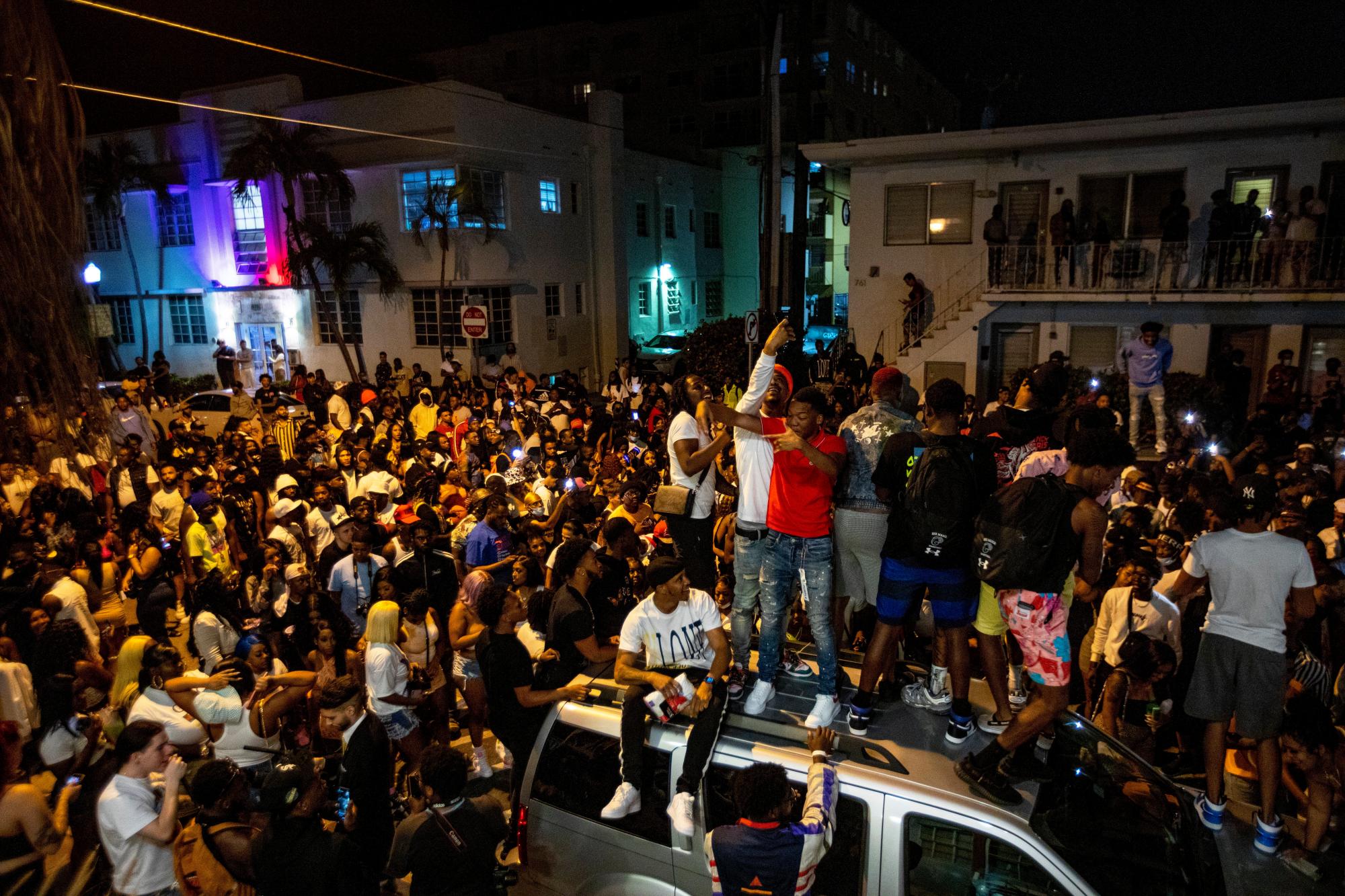Las multitudes se reúnen desafiantes en la calle mientras un orador toca música una hora después del toque de queda en Miami Beach, Florida, el domingo 21 de marzo de 2021. A las 8 p.m. El toque de queda se extendió en Miami Beach después de que las fuerzas del orden trabajaron para contener a las multitudes rebeldes de turistas durante las vacaciones de primavera.