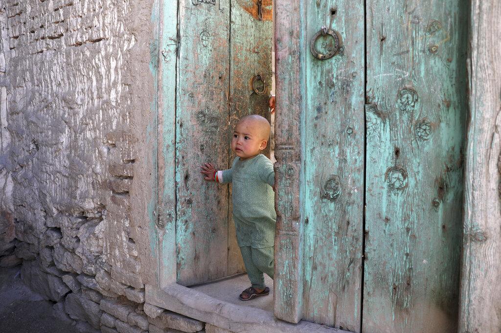 Un niño afgano se asoma a la puerta de su casa en Kabul, Afghanistan (AP Photo/Rahmat Gul)