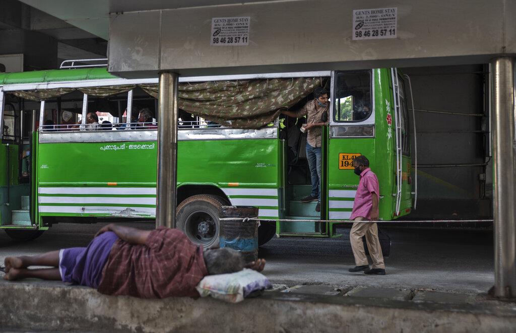 El operador de un autobús espera por los pasajeros mientras un hombre duerme en el pavimento en una calle de Kochi, estado de Kerala, en La India. (AP Photo/R S Iyer)