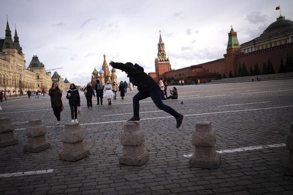 Un joven se divierte saltando sobre los pilotillos que marcan el límite para el paso vehicular en la Plaza Roja de Moscú, en Rusia.  (AP Photo/Alexander Zemlianichenko)