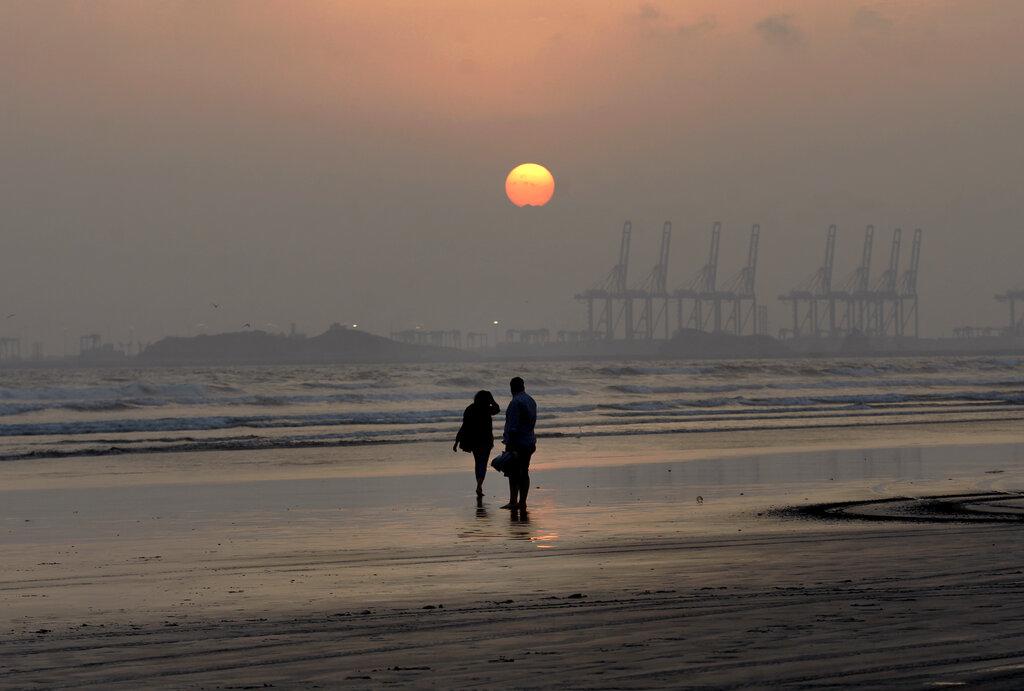Una pareja camina en la playa Clifton mientras mira el atardecer en Karachi, Pakistan. (AP Photo/Fareed Khan)