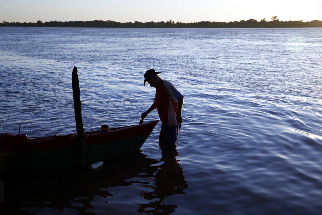 Cipriano Villanueva pinta su bote pesquero en las aguas del Río Paragua, en Asunción, Paraguay. (AP Photo/Jorge Saenz)