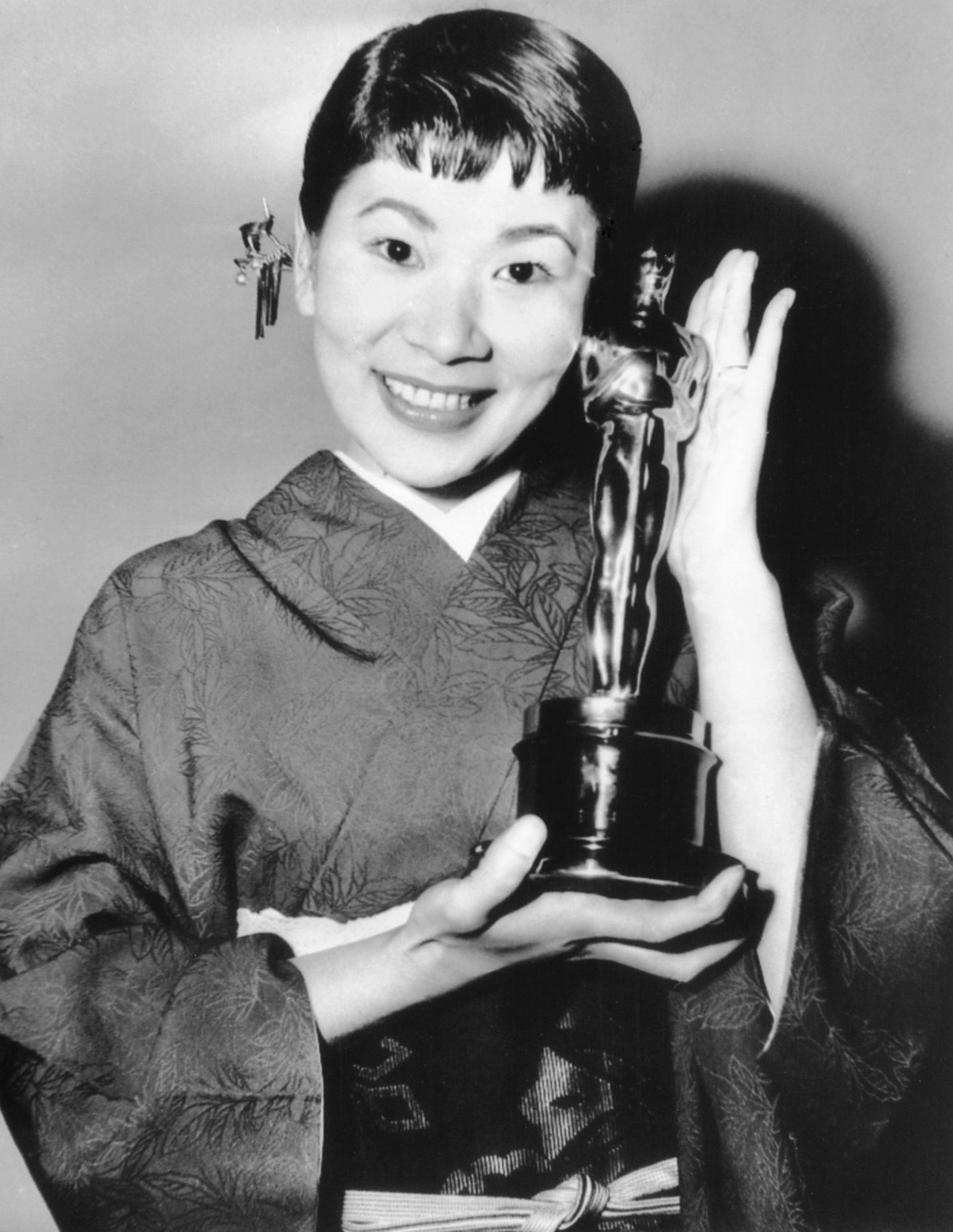 La actriz japonesa Miyoshi Umeki posa con el Premio de la Academia a mejor actriz de reparto por su papel en Sayonara, mientras el presentador Anthony Quinn la mira en los Premios de la Academia en Los Angeles el 26 de marzo de 1958. Umeki es la primera persona de Japón en ganar un Oscar.