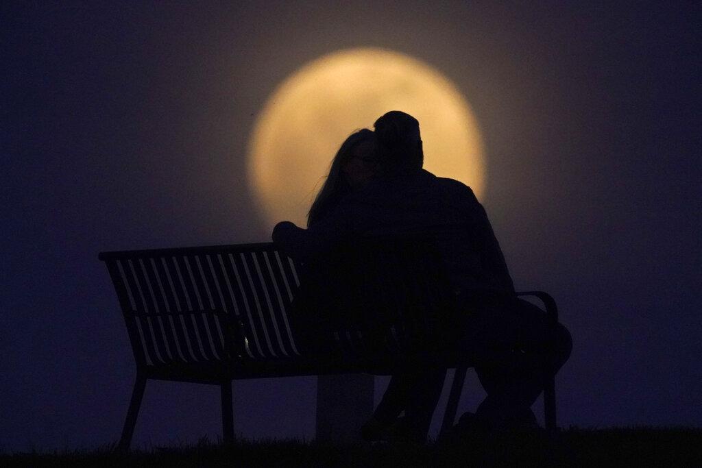 Una pareja mira la luna desde un banco en un parque ubicado en New Albany, Indiana. La luna se encontró en el punto más cercano de su órbita a la tierra.  (AP Photo/Charlie Riedel)