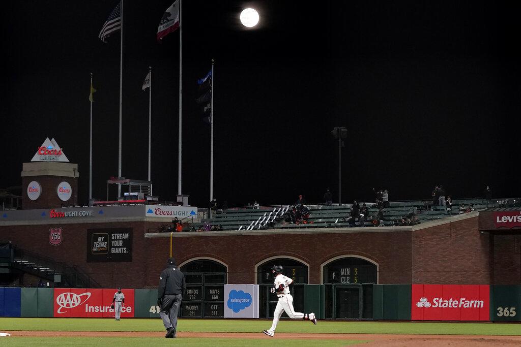 Buster Posey, de los Gigantes de San Francisco, da la vuelta al cuadro en un juego de Grandes Ligas mientras la luna llena ilumina el cielo de la ciudad de San Francisco. (AP Photo/Jeff Chiu)