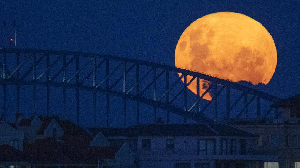 El puente sobre el puerto de Sydney, en Australia, es iluminado por la luz de la superluna rosa del 26 de abril de 2021. (AP Photo/Mark Baker)