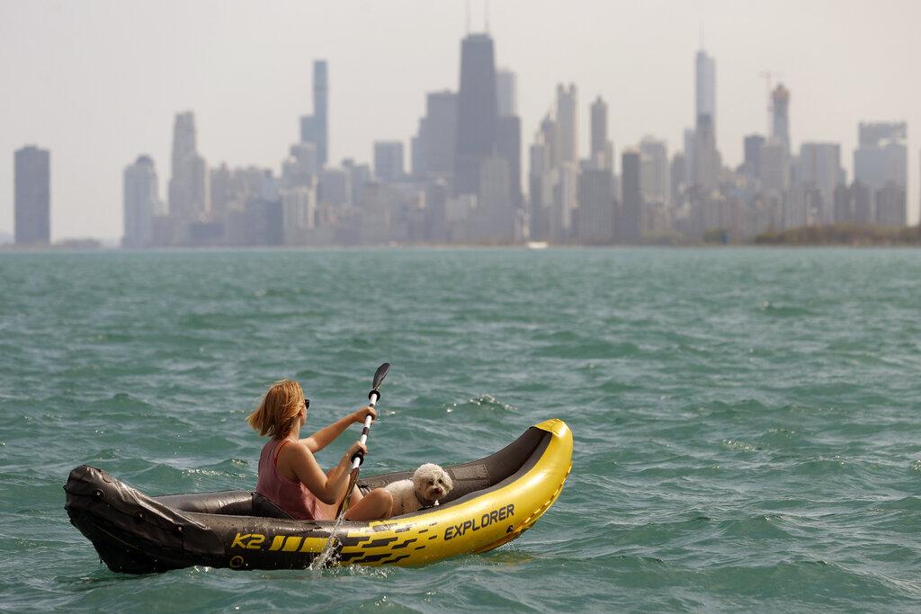 Una mujer y su perro navegan en el Lago Michigan, en Chicago. (AP Photo/Shafkat Anowar)