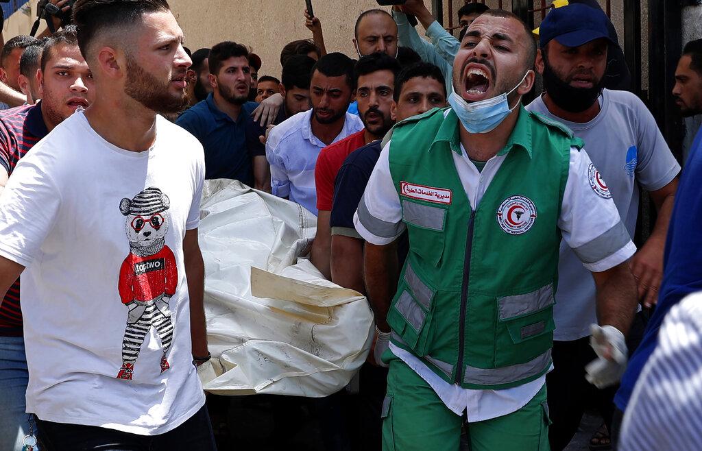 Medicos y jóvenes cantan mientras transportan el cuerpo sin vida de un hombre luego de los ataques israelíes que alcanzaron el edificio en el que vivía.  (AP Photo/Adel Hana)