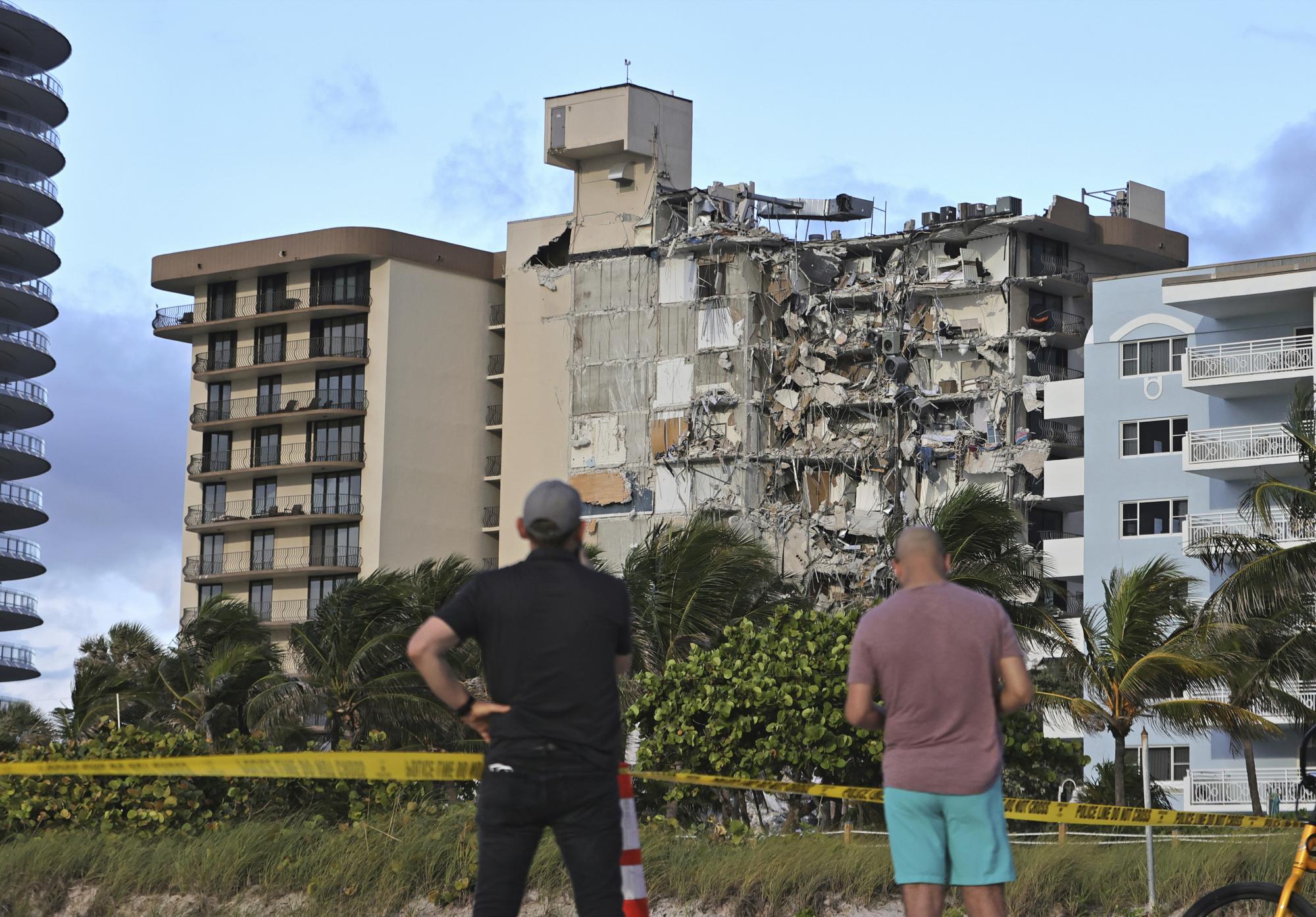 Dos personas miran el condominio Champlain Towers parcialmente derrumbado en Surfside, Florida, el jueves 24 de junio de 2021 (David Santiago / Miami Herald vía AP).
