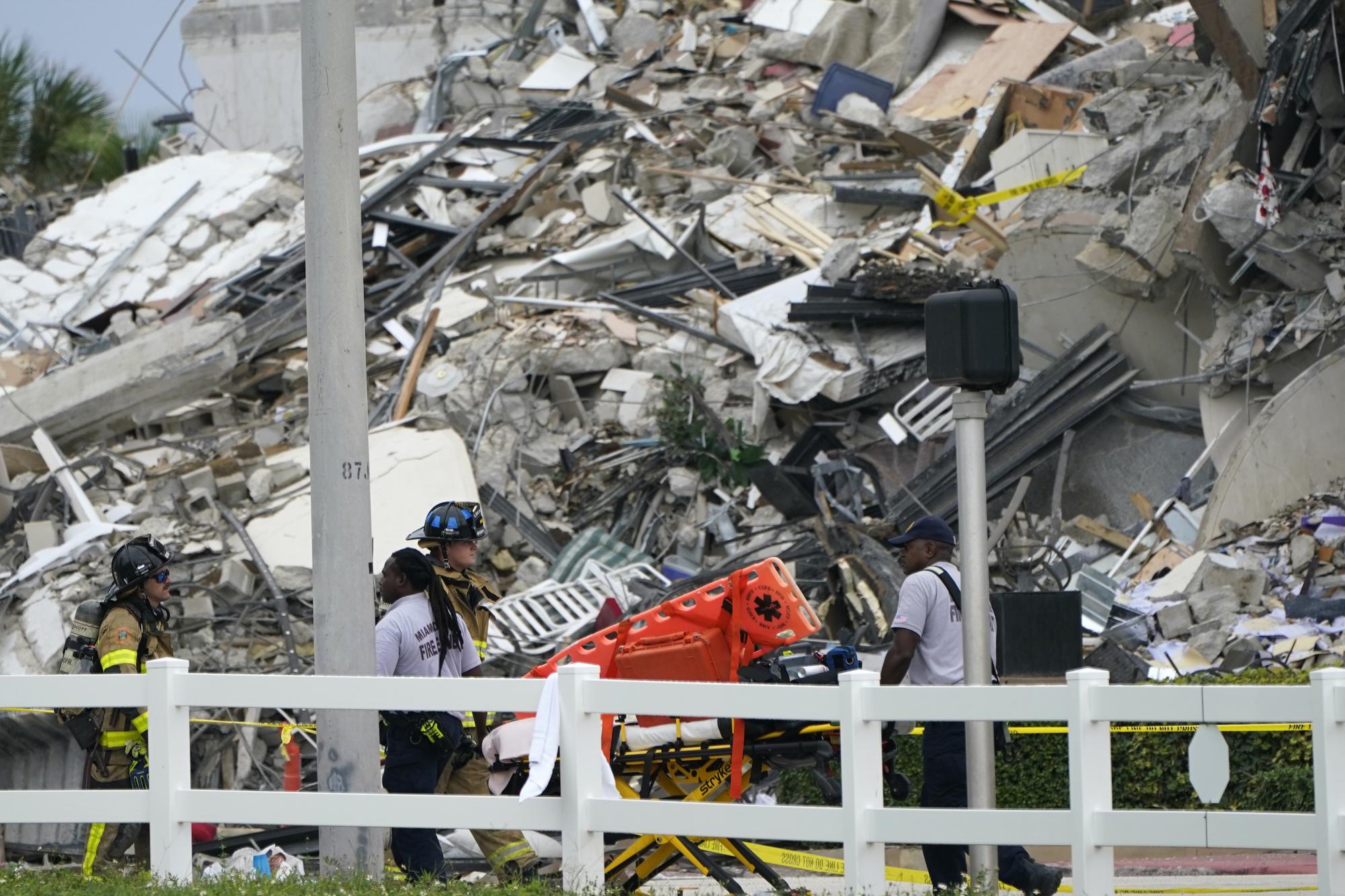 El personal del Cuerpo de Bomberos de Miami-Dade camina con una camilla vacía frente a la escena donde se derrumbó un ala de un edificio de condominios frente a la playa de 12 pisos, el jueves 24 de junio de 2021, en el área de Surfside de Miami. (Foto AP / Lynne Sladky)