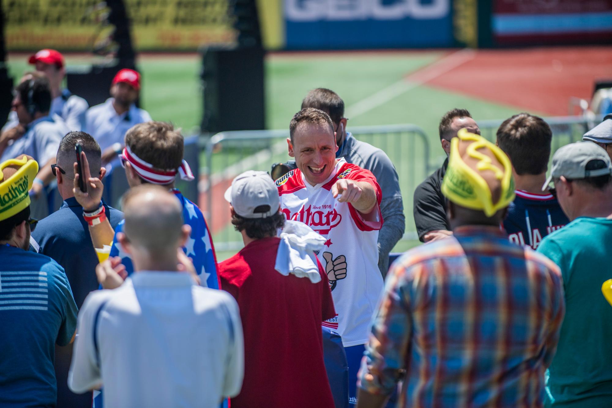 Joey Chestnut, centro, interactúa en el concurso Nathan's Famous Fourth of July International Hot Dog-Eating Contest en el Mainonides Park en la isla Coney el domingo 4 de julio de 2021 en Nueva York. 