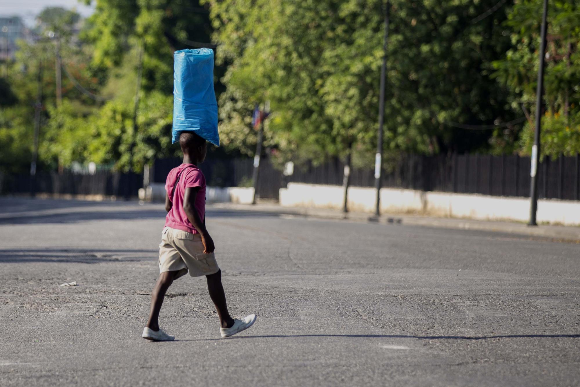 Un vendedor cruza una calle vacía de tráfico cerca del Palacio Nacional en Puerto Príncipe, Haití, el miércoles 7 de julio de 2021.  (Foto AP / Joseph Odelyn)
