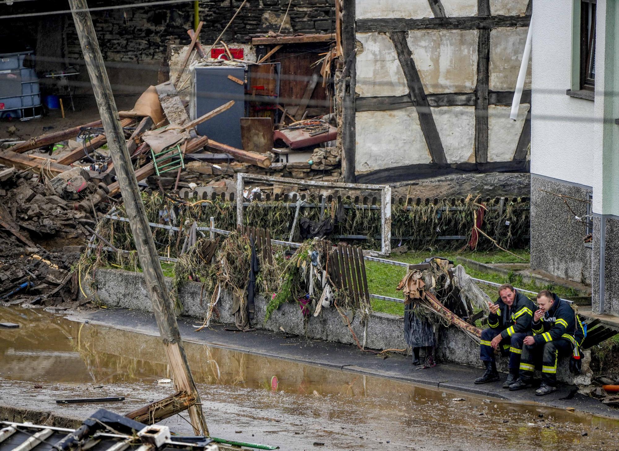 Los bomberos descansan junto a los escombros de las casas en Schuld, Alemania, el viernes 16 de julio de 2021. Dos días antes de que el río Ahr se desbordara por las fuertes lluvias que causaron varias muertes y cientos de desaparecidos. (AP Photo/Michael Probst)