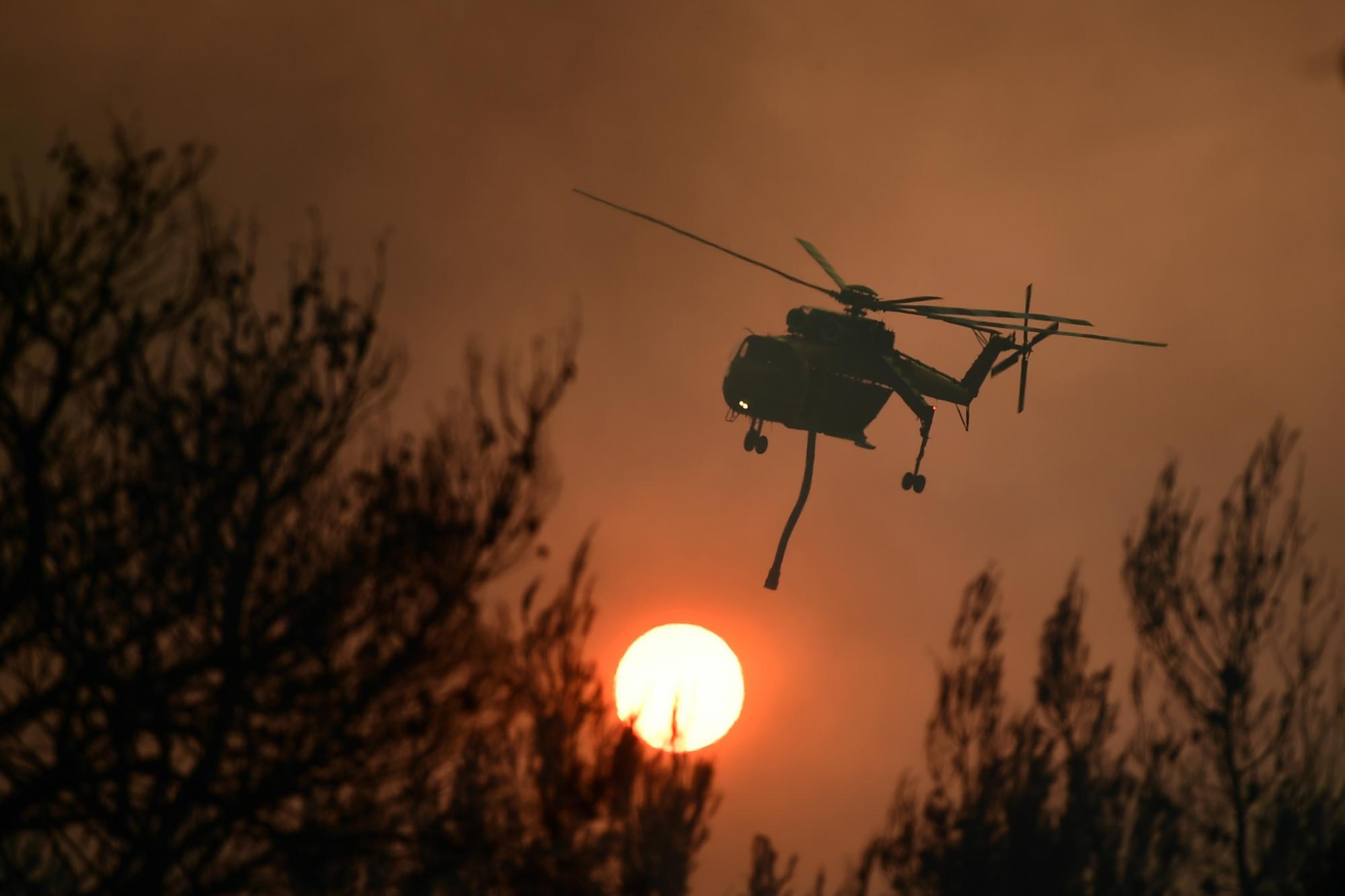 Un helicóptero opera durante un incendio forestal en el área de Kryoneri, en el norte de Atenas, Grecia. (AP Photo/Michael Varaklas)