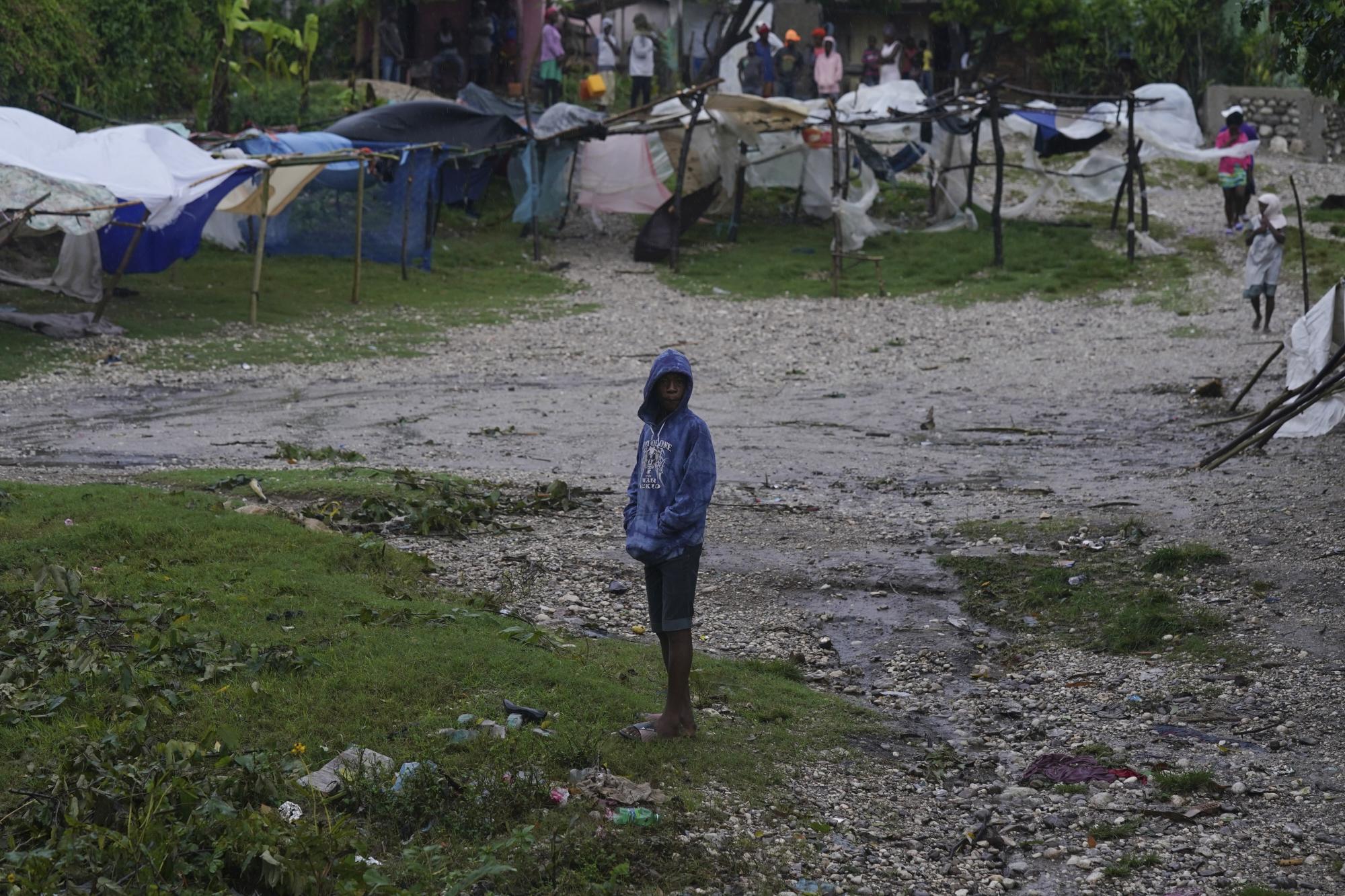 Una persona se para en medio de tiendas de campaña instaladas por personas desplazadas por el terremoto de magnitud 7,2 la mañana después de que la tormenta tropical Grace azotara Les Cayes, Haití, el martes 17 de agosto de 2021, tres días después del terremoto. (Foto AP / Fernando Llano)