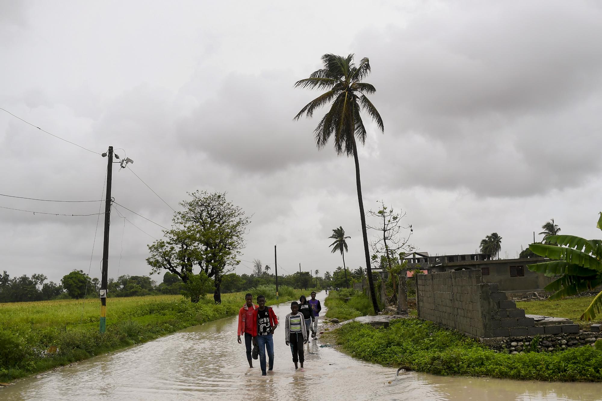 Los residentes atraviesan una carretera inundada la mañana después de que la tormenta tropical Grace azotara Trou Mahot, Haití, el martes 17 de agosto de 2021, tres días después de un terremoto de magnitud 7,2. (AP Photo/Matias Delacroix)