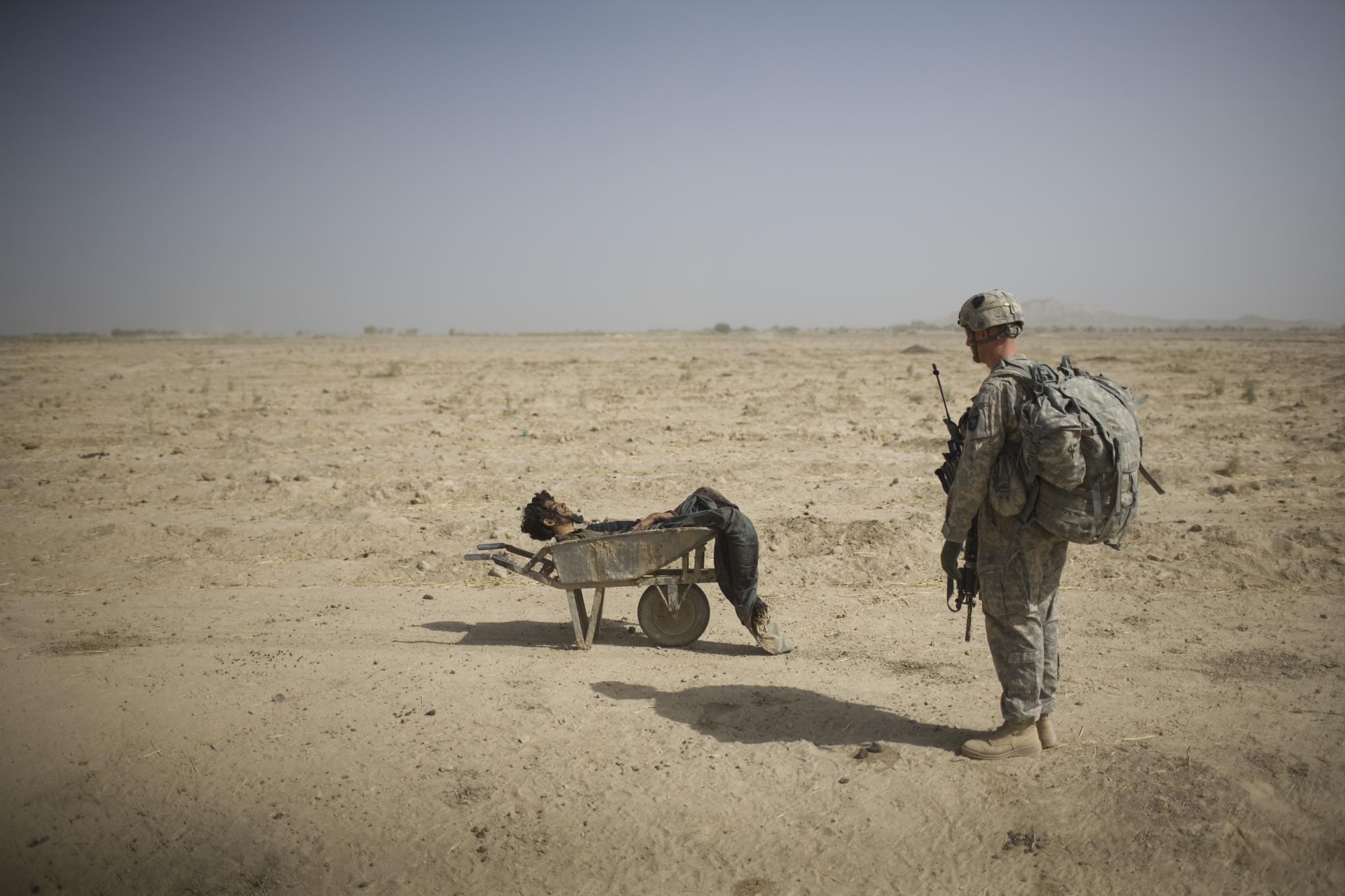 Un soldado del Ejército de los EE. UU. Del Regimiento de Infantería 502 del Pelotón Scout, 101ª División Aerotransportada, observa el cuerpo de un presunto emplazador de artefactos explosivos improvisado talibán que murió en un ataque con misiles de la coalición en el distrito de Zhari, provincia de Kandahar, el domingo 10 de octubre de 2010. Los Scouts La misión era apoyar los esfuerzos de remoción de bombas al borde de la carretera en el bastión militante, la última fase de la Operación Dragon Strike que duró varios días. (Foto AP / Rodrigo Abd)