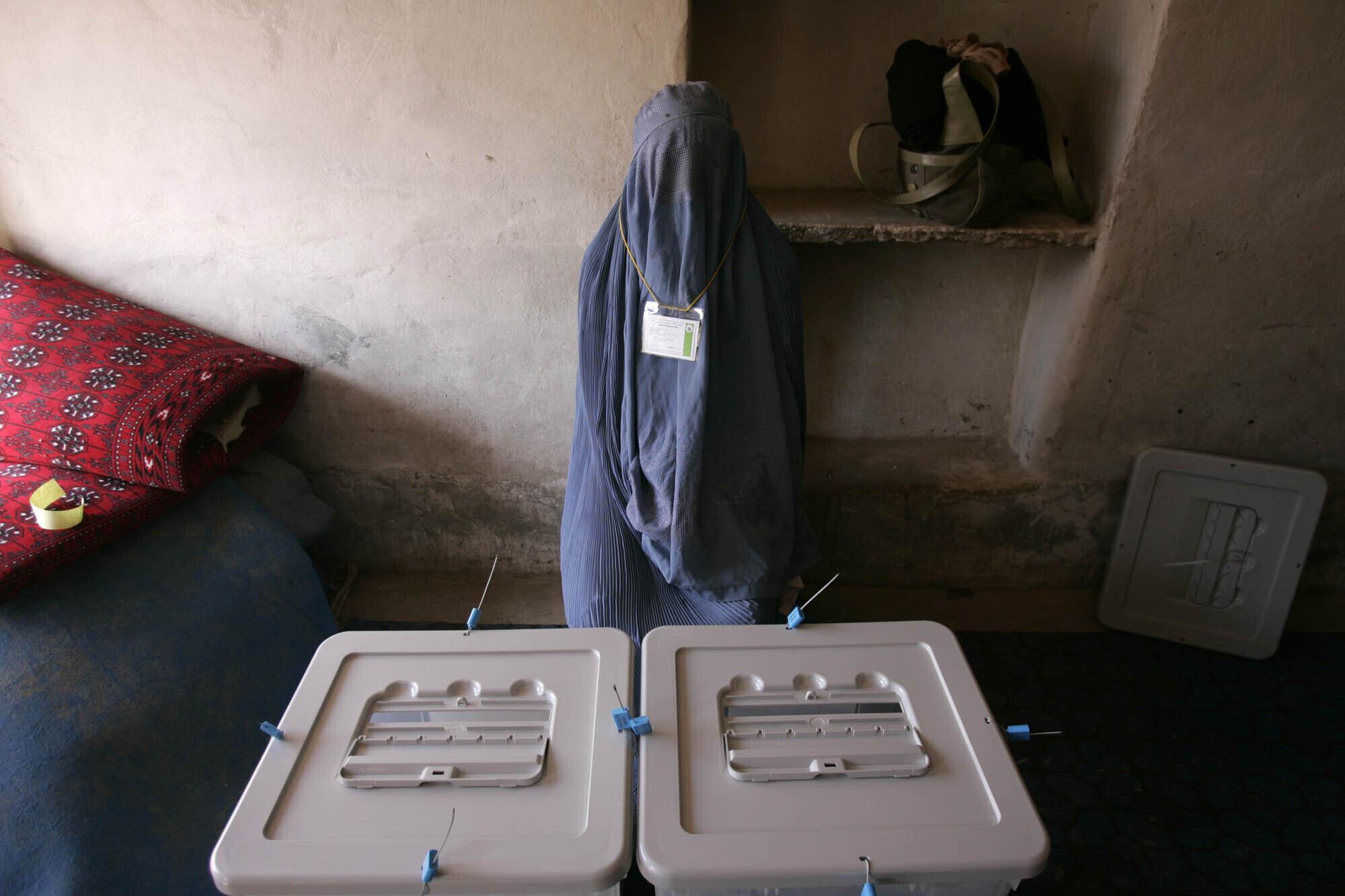 Una trabajadora electoral espera que los votantes lleguen a un colegio electoral en Kandahar, Afganistán, el 18 de septiembre de 2005. Afganistán celebró elecciones parlamentarias históricas, las primeras en tres décadas. (Foto AP / Saurabh Das)