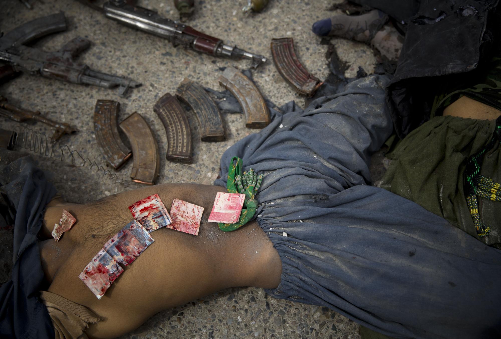 Los billetes de banco paquistaníes cubiertos de sangre se muestran en el cuerpo de un atacante suicida muerto después de que la policía los encontrara en su bolsillo en el centro de Kandahar, Afganistán, el miércoles 12 de marzo de 2014, luego de un ataque contra la antigua sede de inteligencia afgana. Funcionarios policiales dijeron que tres insurgentes que intentaron asaltar la antigua sede del servicio de inteligencia de Afganistán en el sur de Kandahar murieron en un tiroteo con las fuerzas de seguridad. (Foto AP / Anja Niedringhaus)