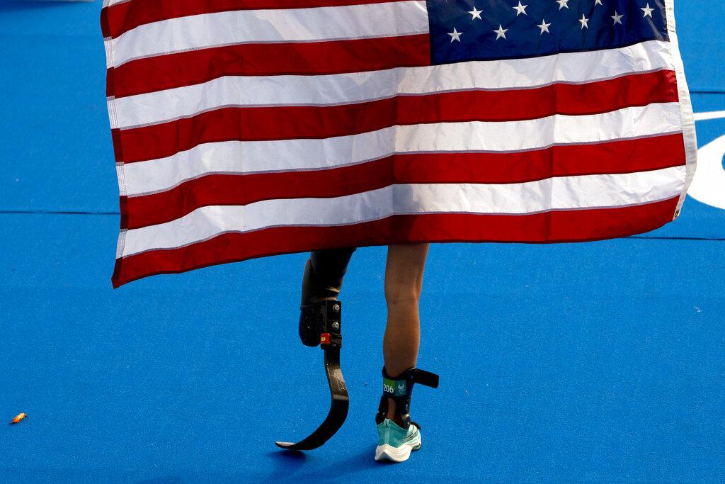 Allysa Seely de Estados Unidos sostiene una bandera de Estados Unidos después de ganar el triatlón femenino PTS2 en el Parque Marino de Odaiba en los Juegos Paralímpicos de 2020 en Tokio, el sábado 28 de agosto de 2021 (AP Photo / Emilio Morenatti).