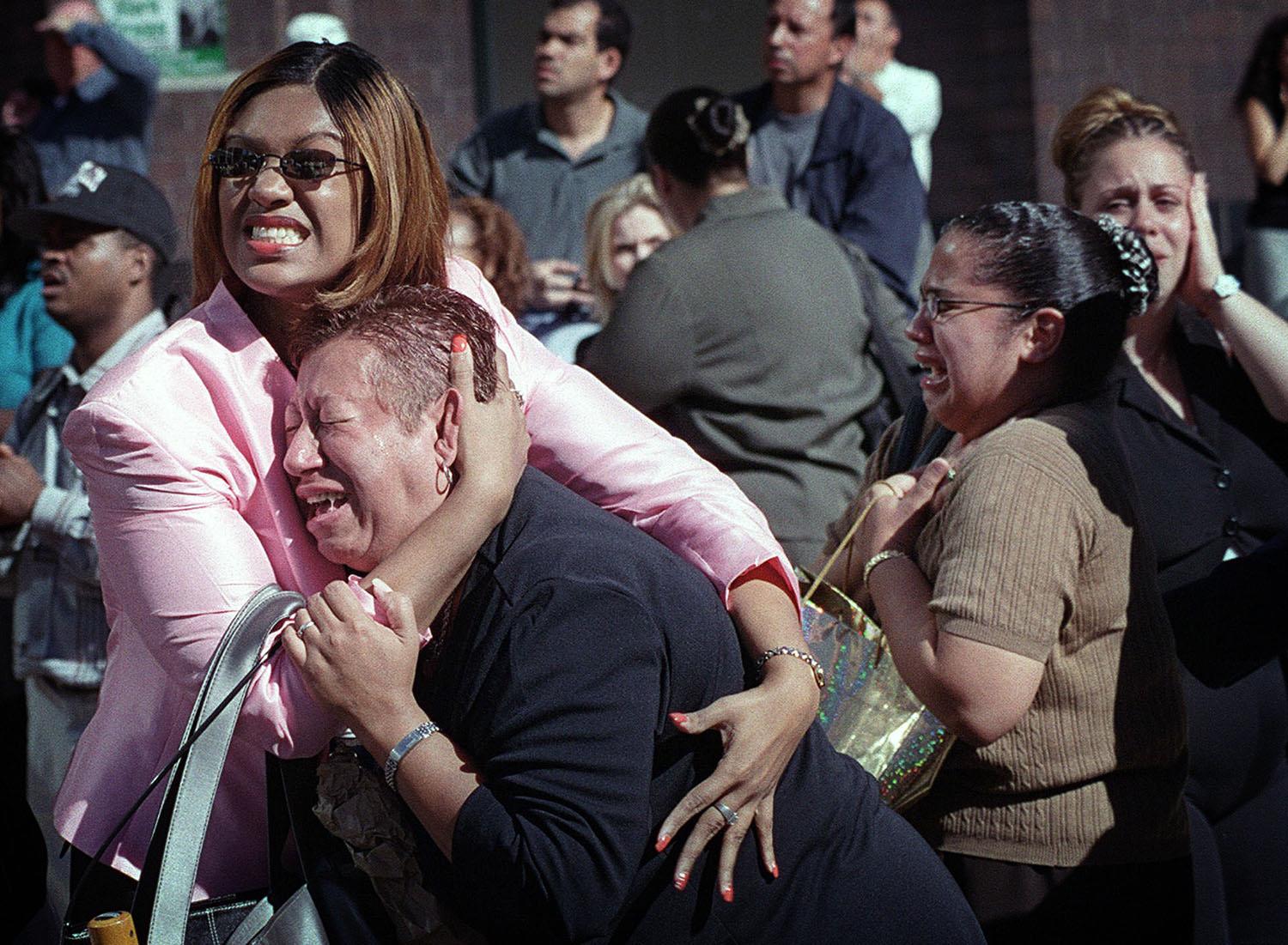 Dos mujeres se abrazan mientras ven arder el World Trade Center en Nueva York el martes 11 de septiembre de 2001. (AP Photo / Ernesto Mora)