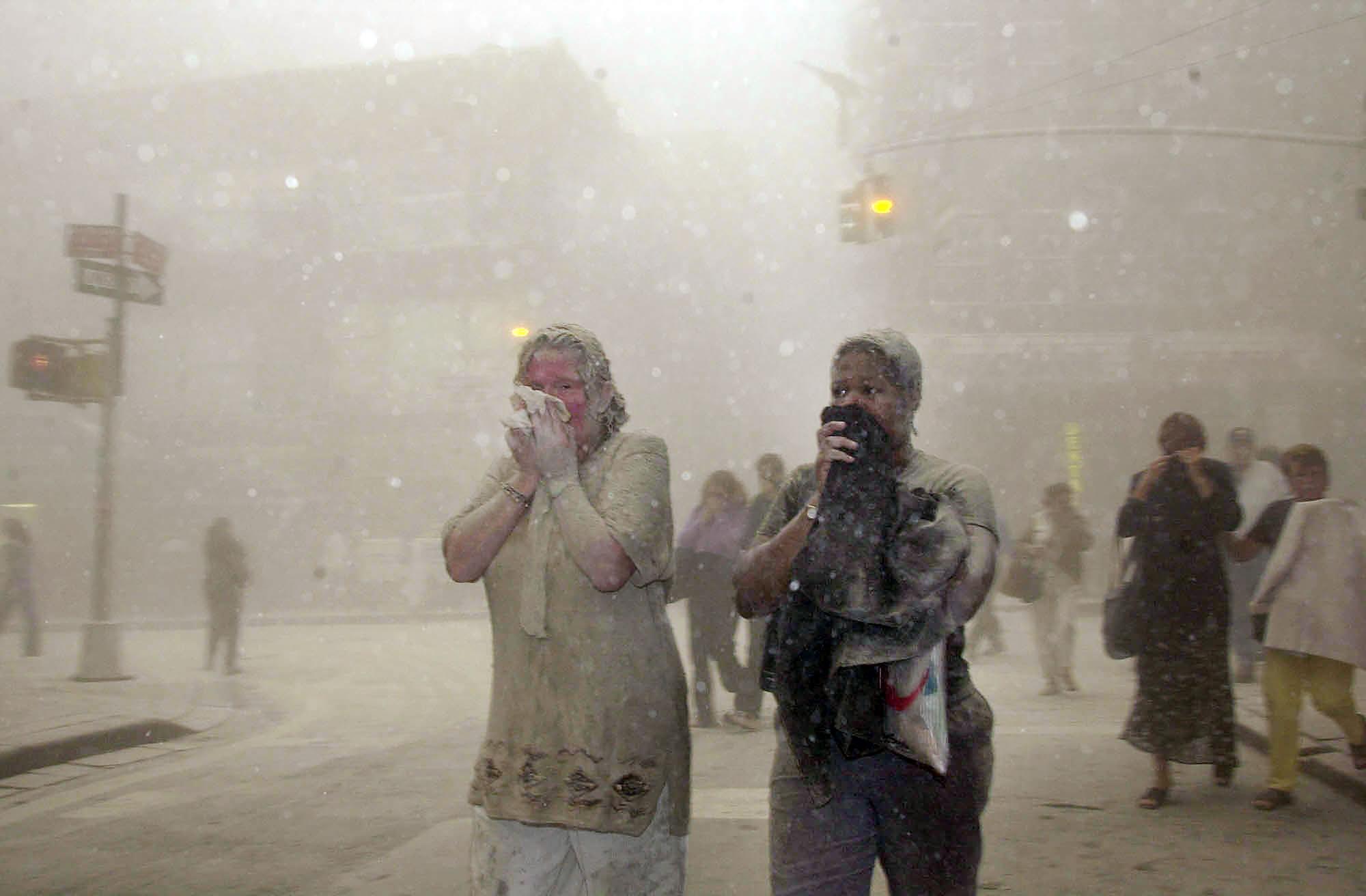 ARCHIVO - En esta foto de archivo del 11 de septiembre de 2001, personas cubiertas de polvo de los edificios derrumbados del World Trade Center, caminan por el área, en Nueva York. Dos décadas después del colapso de las torres gemelas, la gente sigue denunciando enfermedades que podrían estar relacionadas con los ataques. (Foto AP / Suzanne Plunkett, archivo)