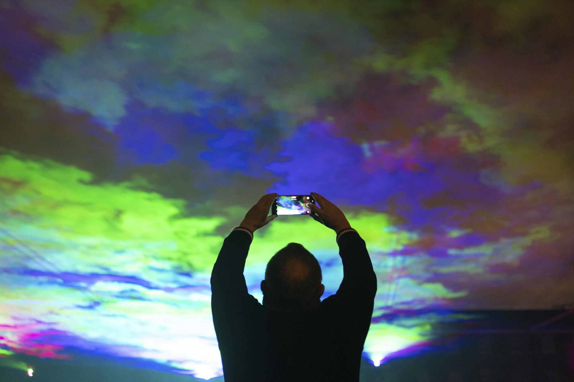 Una persona ve Borealis, una instalación de arte con luz láser de Dan Acher que recrea la aurora boreal, como parte del Festival intencional de Greenwich y Docklands en el Royal Artillery Barracks en el distrito de Woolwich de Londres, el viernes 10 de septiembre de 2021. ( Dominic Lipinski / PA vía AP)