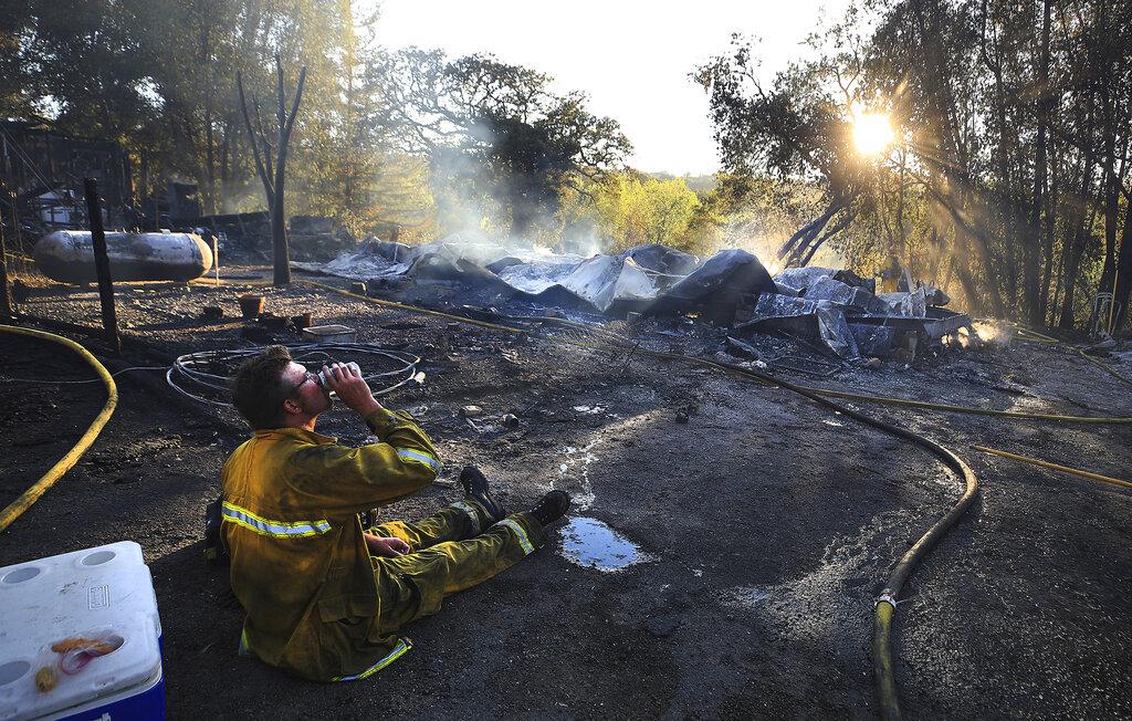 Waylon Hockemier, de Redwood Valley Fire, se hidrata después de combatir el incendio de Hopkins a lo largo de East Calpella Road el domingo 12 de septiembre de 2021 en Calpella, California (Kent Porter / The Press Democrat vía AP)