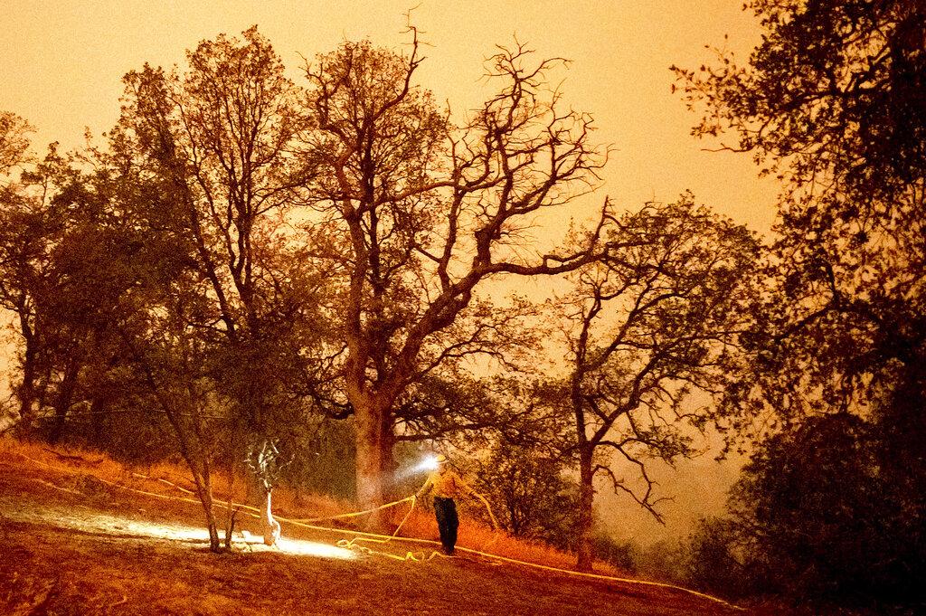 Un bombero coloca una manguera alrededor del Foothills Visitor Center mientras lucha contra el KNP Complex Fire en el Parque Nacional Sequoia, California, el martes 14 de septiembre de 2021. El incendio arde cerca del Giant Forest, hogar de más de 2.000 secuoyas gigantes. (Foto AP / Noah Berger)
