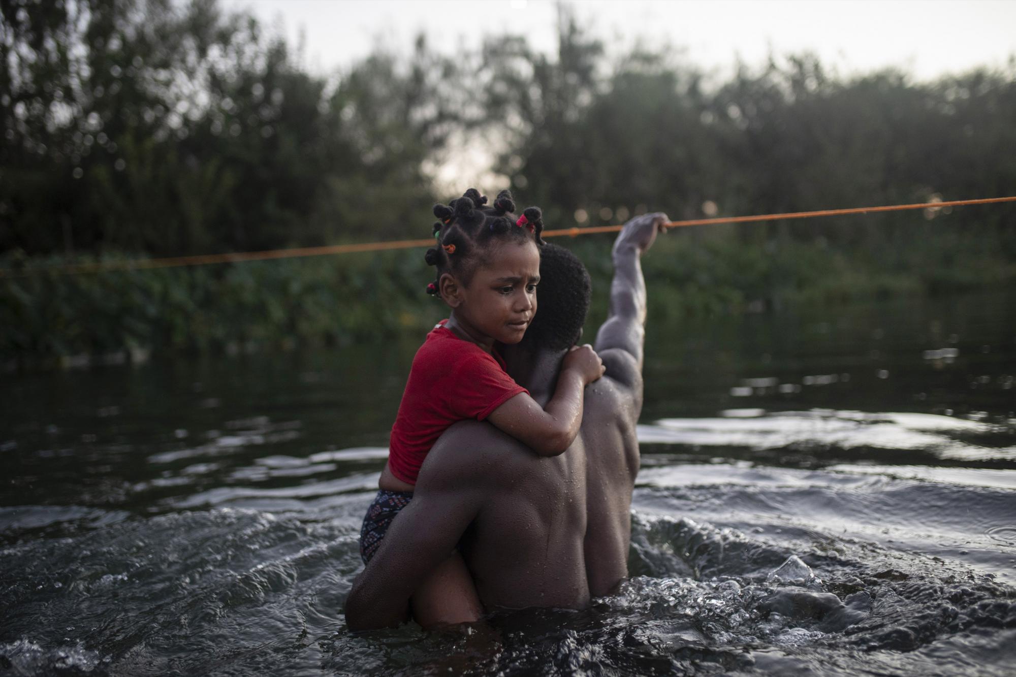 Una niña haitiana llora mientras cruza el Río Grande en los brazos de un adulto. (Foto AP / Félix Márquez)