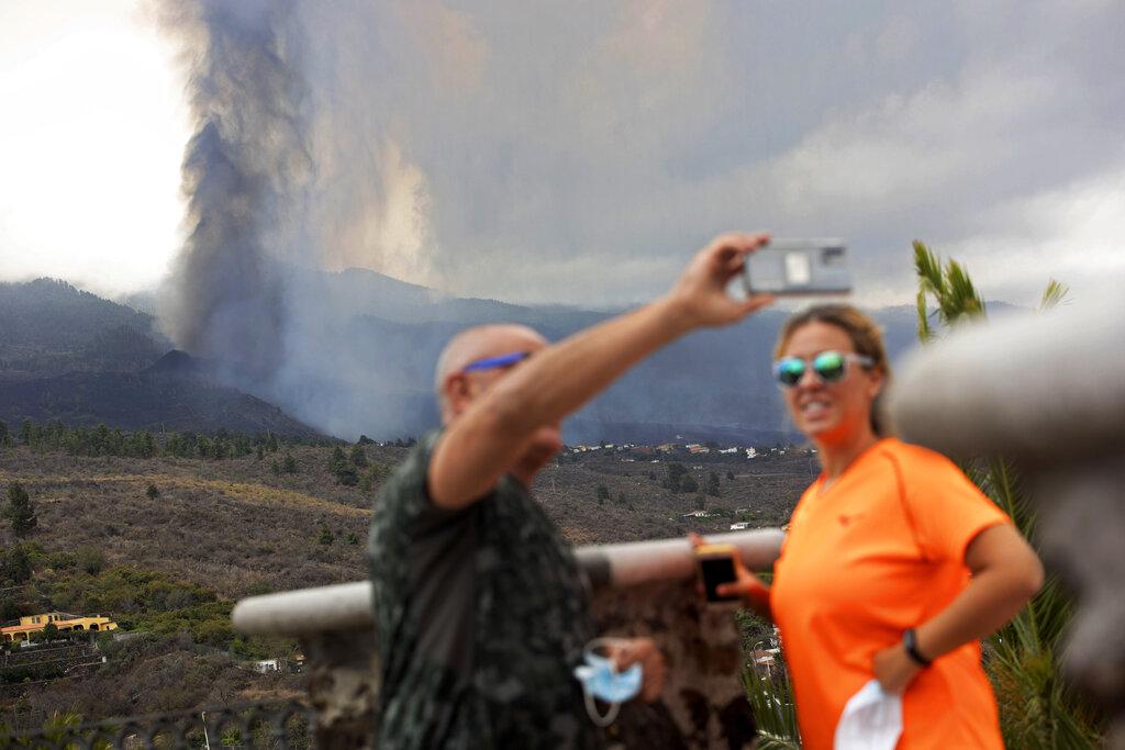 Una pareja se toma selfies frente a la erupción de un volcán cerca de El Paso en la isla de La Palma en las Canarias, España. Las autoridades dicen que no esperan ninguna otra erupción y que actualmente no hay vidas en peligro. (Foto AP / Gerardo Ojeda)