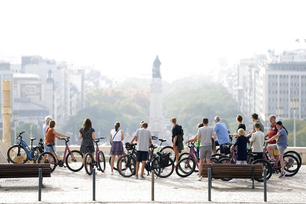 Un grupo de ciclistas mira hacia el centro de Lisboa envuelto en una niebla matutina, el viernes 24 de septiembre de 2021. (AP Photo / Armando Franca)