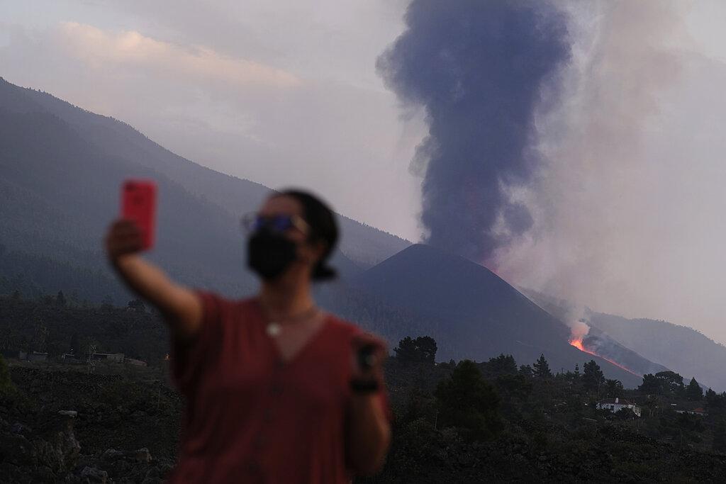 Una mujer se toma una selfie mientras la lava fluye desde un volcán en la isla canaria de La Palma, España, el lunes 27 de septiembre de 2021.  (Foto AP / Daniel Roca)