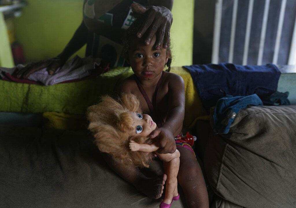 Eloa, de 2 años, mira a la cámara mientras su abuela Lady Laurentino, de 74 años, la acaricia, en su casa en la favela Jardim Gramacho de Río de Janeiro, Brasil, el lunes 4 de octubre de 2021. (AP Photo/Silvia Izquierdo)
