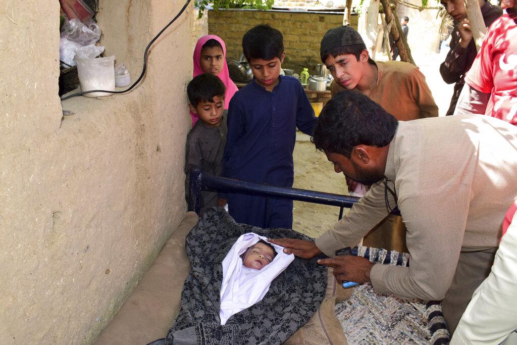 Las personas se paran alrededor del cadáver de un niño después de un terremoto en Harnai, a unos 100 kilómetros (60 millas) al este de Quetta, Pakistán, el jueves 7 de octubre de 2021. El poderoso terremoto derrumbó al menos una mina de carbón y docenas de casas de adobe en el suroeste de Pakistán la madrugada del jueves. (Foto AP / Arshad Butt)