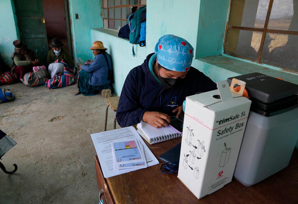 Una trabajadora de la salud espera a los residentes en una reunión para decidir si quieren una inyección de la vacuna de Sinopharm para el COVID-19 durante una campaña de vacunación en una escuela en Mijane, Perú, el jueves 28 de octubre de 2021. 