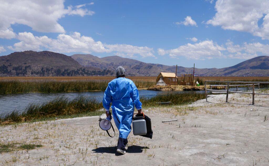 Un trabajador de la salud lleva una hielera llena con dosis de la vacuna de Pfizer para el COVID-19 durante una campaña de vacunación puerta a puerta dirigida a los residentes del lago Titicaca en Puno, Perú, el miércoles 27 de octubre de 2021.  