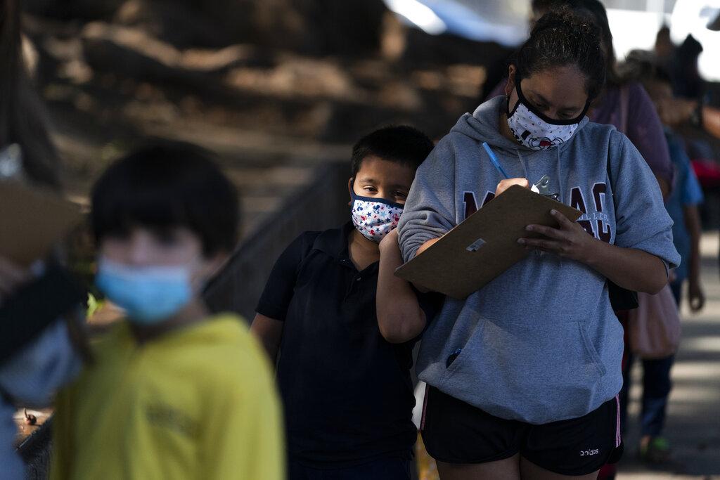 Eric Aviles, 6,  leans on his mother, Catherine, while waiting in line to receive the Pfizer COVID-19 vaccine at a pediatric vaccine clinic for children ages 5 to 11 set up at Willard Intermediate School in Santa Ana, Calif., Tuesday, Nov. 9, 2021. (AP Photo/Jae C. Hong)
