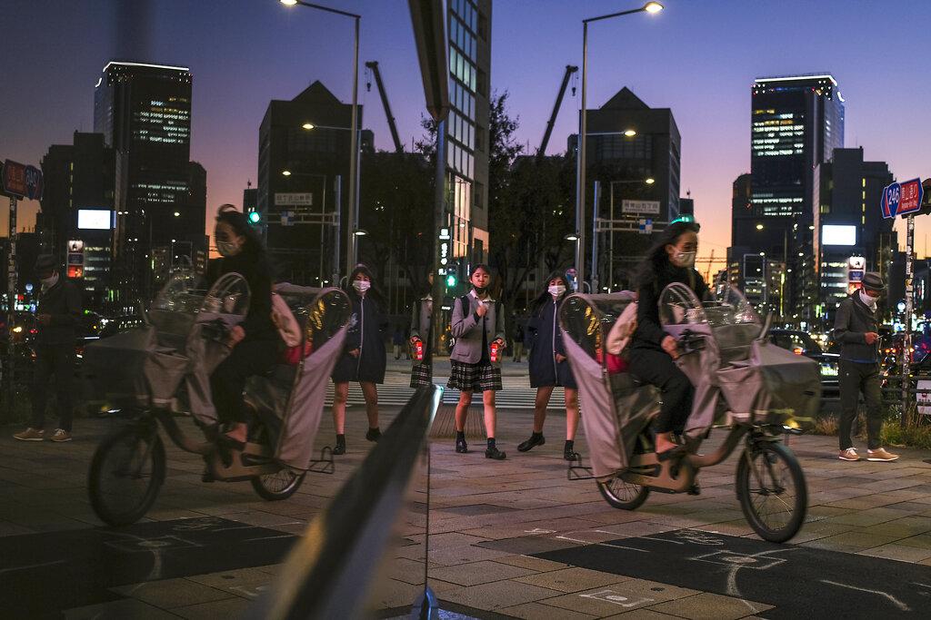 Los residentes se mueven a lo largo de la acera mientras se pone el sol en el área de Aoyama en Tokio, el miércoles 10 de noviembre de 2021.Las restricciones para salir a cenar y otras actividades cotidianas se han aliviado después de que los casos diarios de coronavirus en el país alcanzaron sus niveles más bajos en más de un año. y más del 70% de la población de Japón está vacunada contra COVID-19. (Foto AP / Kiichiro Sato)