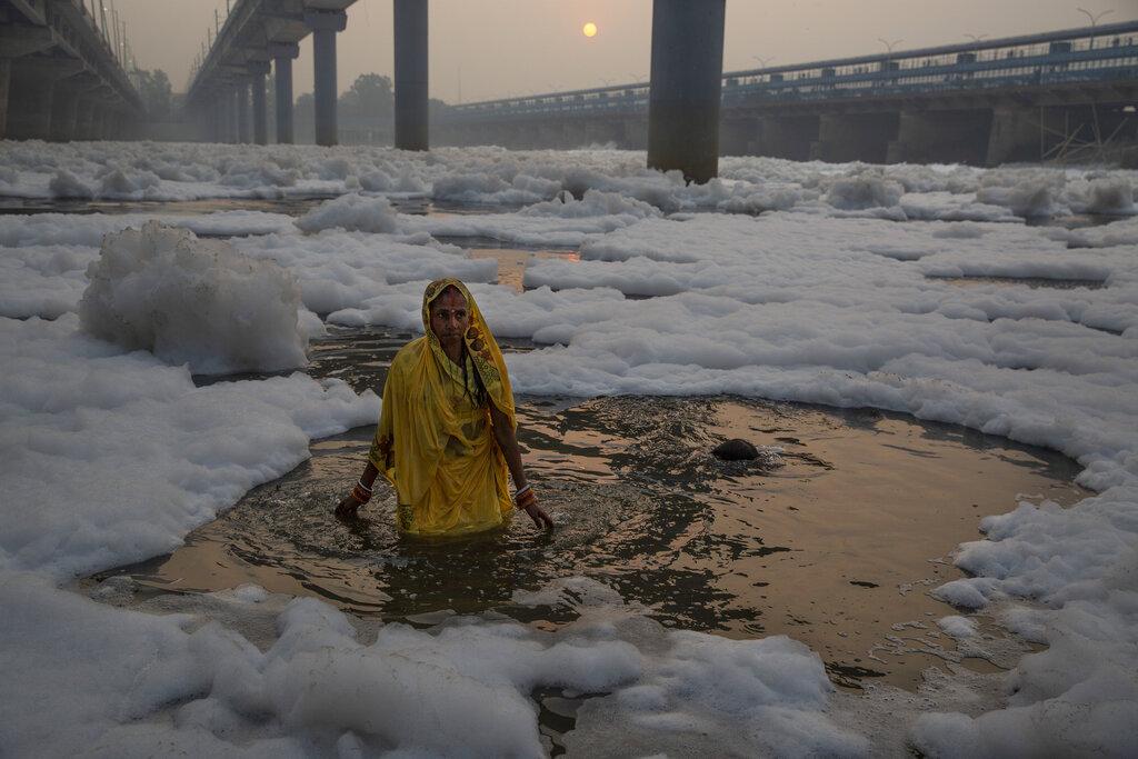 Una devota hindú realiza rituales en el río Yamuna, cubierto de espuma química debido a la contaminación industrial y doméstica, durante el festival Chhath Puja, el miércoles 10 de noviembre de 2021, en Nueva Delhi. (AP Foto/Altaf Qadri)