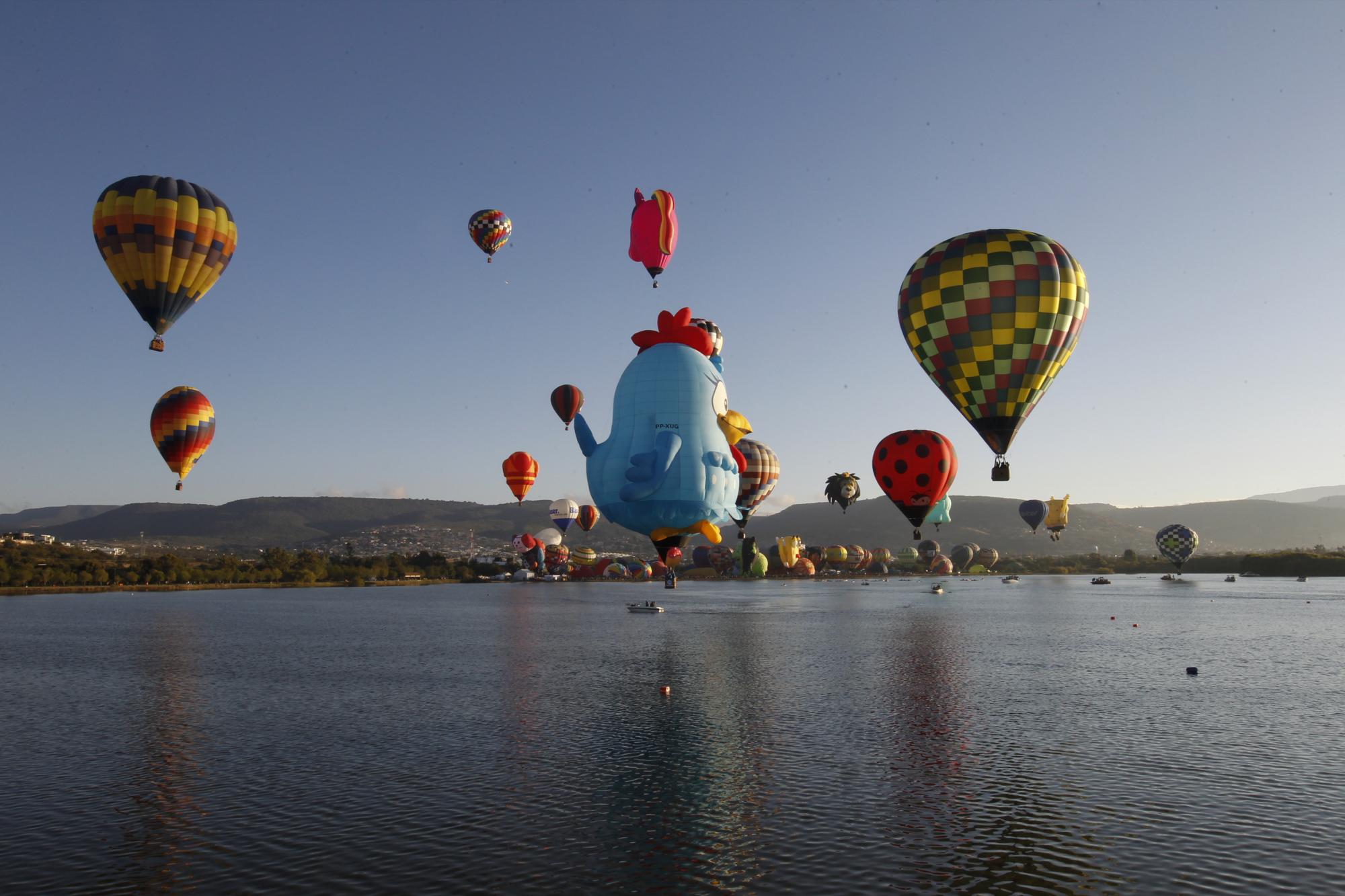 Globos aerostáticos vuelan sobre la presa Papalote durante el Festival Internacional de Globos Aerostáticos en León, México, el viernes 12 de noviembre de 2021 (AP Photo / Mario Armas).