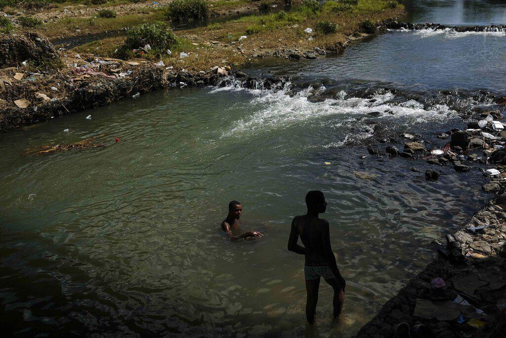 Hombres se bañan en el río Masacre en la frontera entre República Dominicana y Haití en Ouanaminthe, Haití, el viernes 19 de noviembre de 2021. (Foto AP / Matias Delacroix)