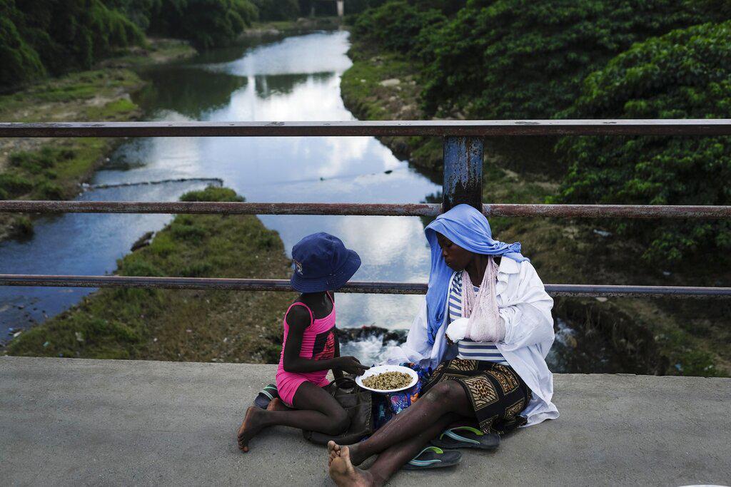 Una mujer come con su hija en un puente fronterizo entre República Dominicana y Haití en Dajabón, República Dominicana, el viernes 19 de noviembre de 2021. (Foto AP / Matias Delacroix)