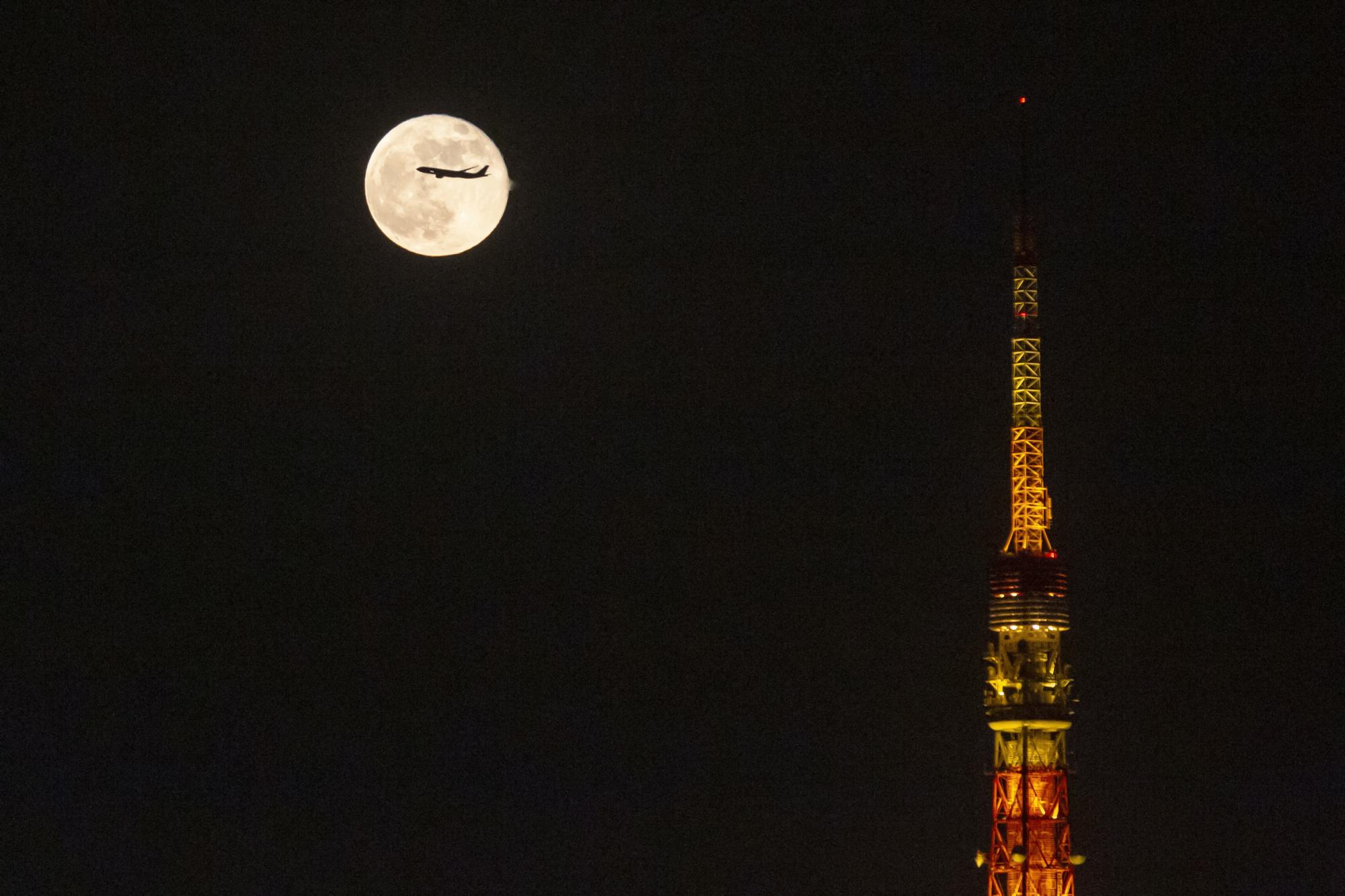 Un avión sobrevuela la luna elevándose sobre la Torre de Tokio el sábado 20 de noviembre de 2021 en Tokio. (Foto AP / Kiichiro Sato)