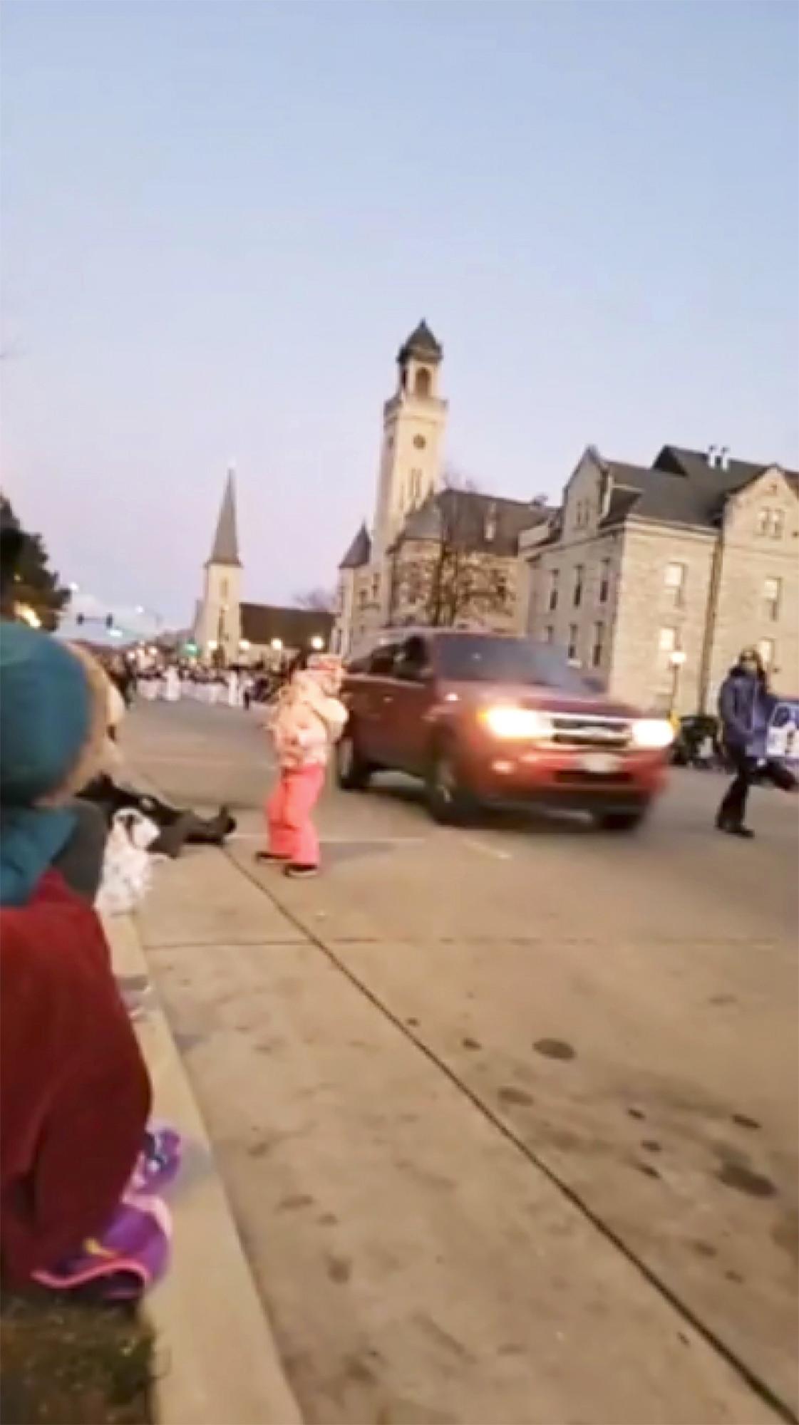 En esta imagen tomada del video, una camioneta pasa a toda velocidad junto a una niña y otras personas que asisten a un desfile de Navidad y continúa conduciendo a través del desfile, hiriendo a varias personas, el domingo 21 de noviembre de 2021 en Waukesha, Wisconsin (Jesús Ochoa vía AP)