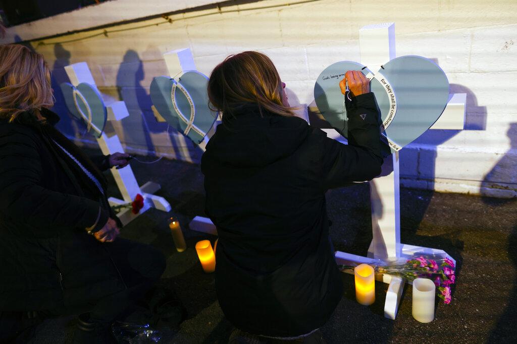La gente escribe mensajes en cruces antes de una vigilia a la luz de las velas en el centro de Waukesha, Wisconsin, el lunes 22 de noviembre de 2021 después de que una camioneta se estrellara en un desfile dominical de Navidad matando a varias personas e hiriendo a decenas. (Foto AP / Jeffrey Phelps)