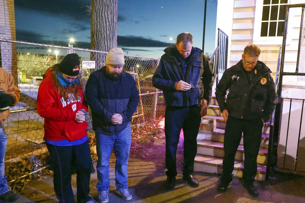 La gente hace una pausa en oración durante una vigilia a la luz de las velas en el centro de Waukesha, Wisconsin, el lunes 22 de noviembre de 2021 después de que una camioneta se estrellara en un desfile dominical de Navidad matando a varias personas e hiriendo a decenas. (Foto AP / Jeffrey Phelps)