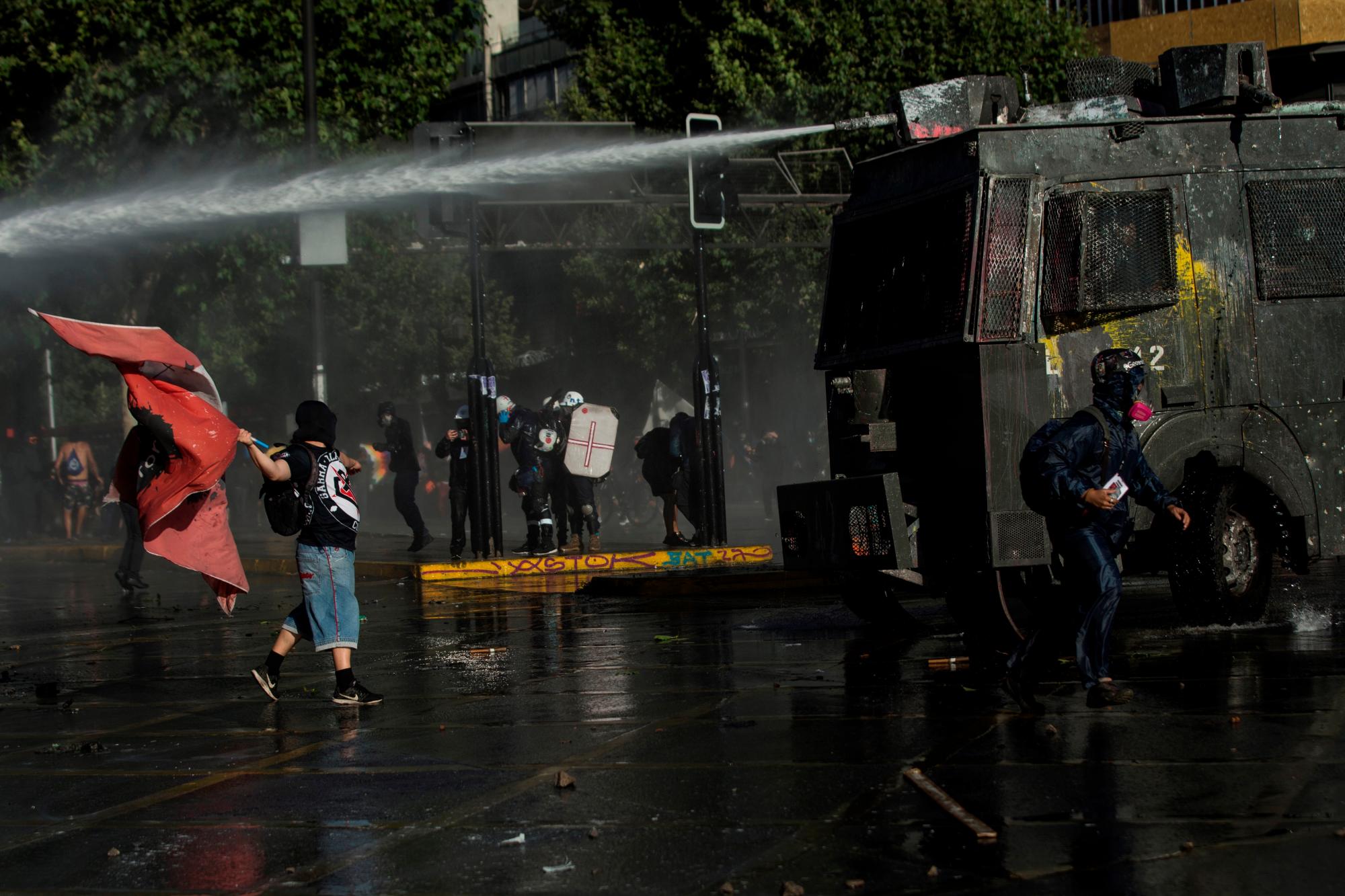 Fuerzas Especiales de Carabineros intentan dispersar a manifestantes que se tomaron la Alameda, principal avenida en Santiago, hoy en Chile.