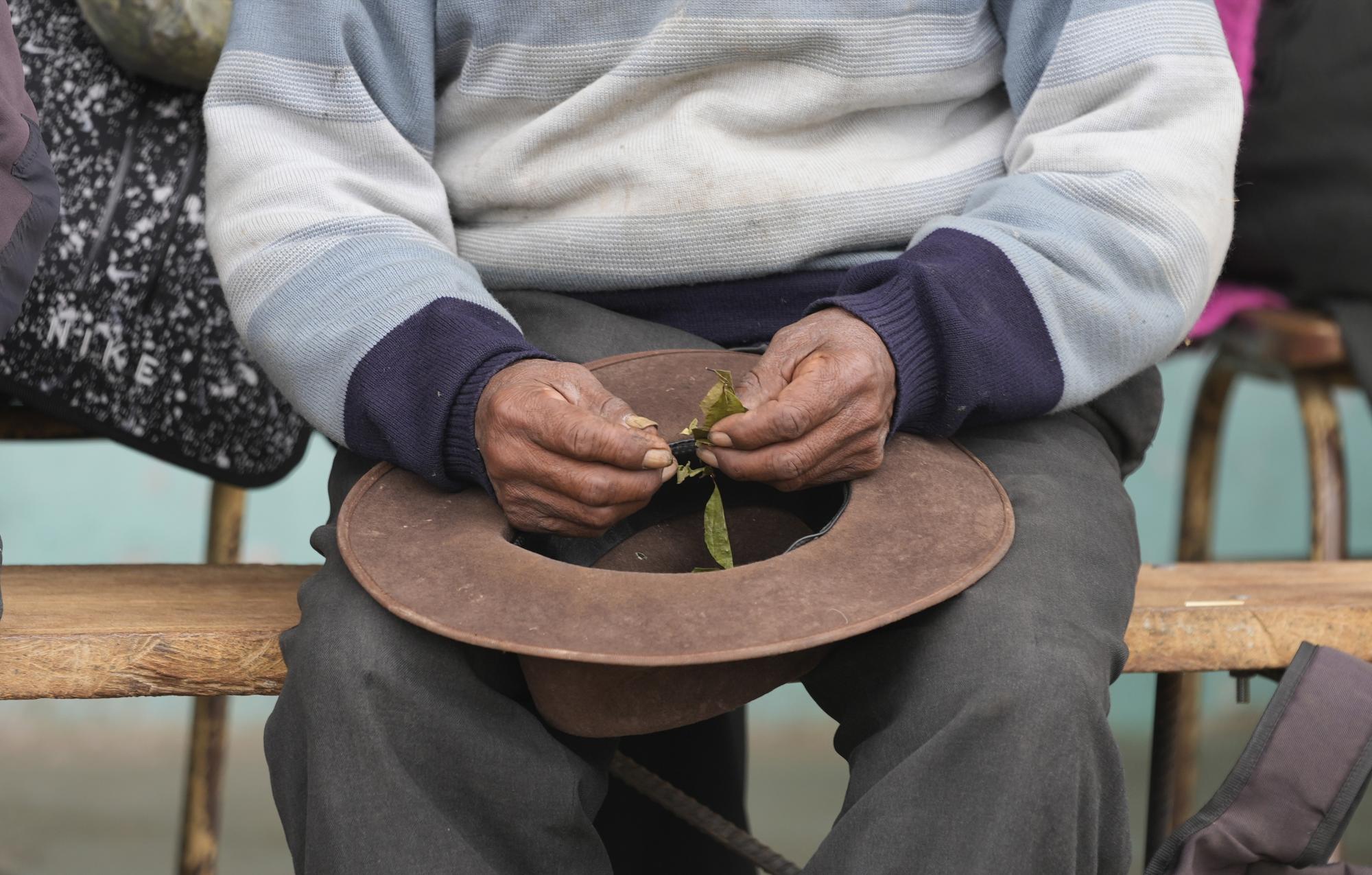 Un residente sostiene hojas de coca durante una reunión comunitaria para discutir si recibirán la vacuna de Sinopharm para el COVID-19, durante una campaña de vacunación en una escuela local en Mijane, Perú, el jueves 28 de octubre de 2021. 