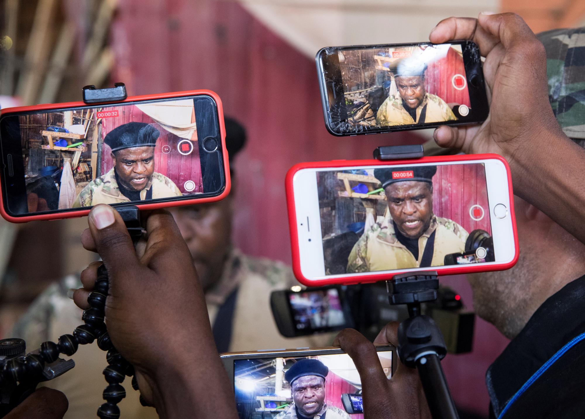 Miembros de la prensa sostienen teléfonos celulares mientras registran las declaraciones del líder de la principal banda armada de Haití, Jimmy Cherizier, alias Barbecue, durante un recorrido hoy por el barrio La Saline, en Puerto Príncipe (Haití). EFE/ Orlando Barría